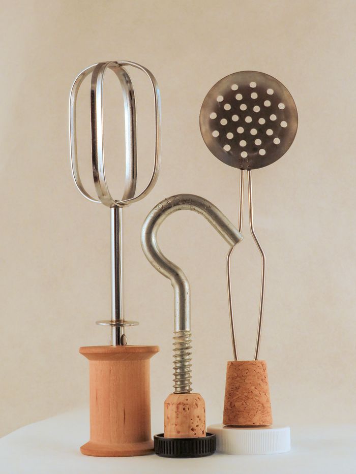 Artistic arrangement of kitchen utensils with corks and metal parts in a playful still life.